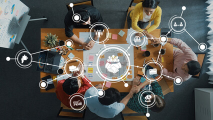 Engaging business strategy session with a diverse team gathered around a table, utilizing digital tools and visual aids for effective collaboration and innovative planning. Amity