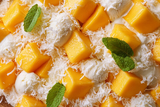 Tropical mango and coconut ice cream topped with fresh fruit slices and mint leaves - an exotic and refreshing take on the popular treat