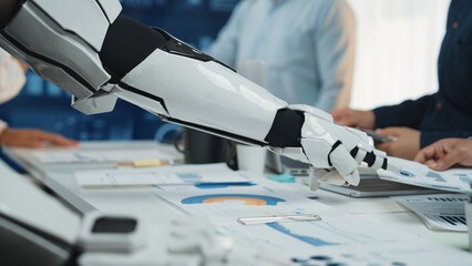 A robotic arm interacts with business professionals in a modern office, showcasing cutting-edge technology for collaboration and innovative solutions in data analysis.Noogenesis