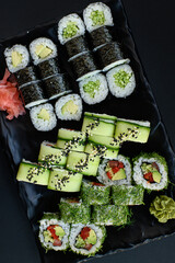 Assorted vegan sushi rolls served on a black plate. Colorful plant-based ingredients arranged in an elegant, minimalistic Japanese food presentation. Top view.