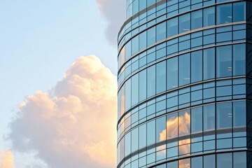 Obraz premium A modern glass building reflecting clouds and sky, showcasing contemporary architecture with curved lines and a sleek design.