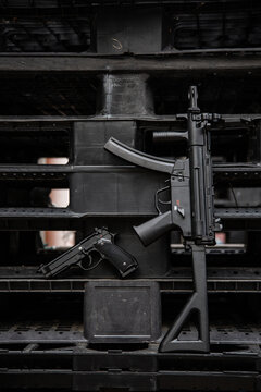 Black submachine gun and pistol laid against industrial plastic structure