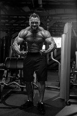 Fototapeta na wymiar athletic man is flexing his muscles in gym setting surrounded fitness equipment. He embodies strength and dedication while engaging in workout for optimal health.