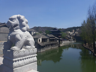 Scenic view of Gubei Water Town in China featuring a traditional stone guardian lion, calm river,...