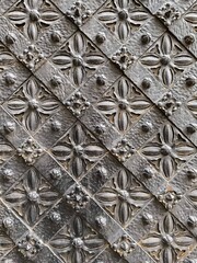 Detailed close-up texture of an antique metal surface with symmetrical floral engraving and geometric patterns, highlighting traditional craftsmanship and gothic style of ornaments