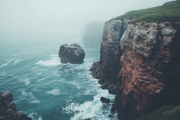 Misty coastal cliffs meet the churning sea