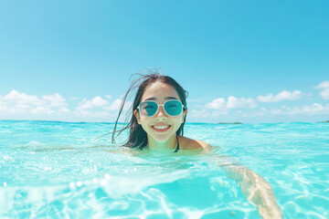 A joyful woman enjoying a refreshing swim in clear blue waters, embodying the spirit of summer and happiness.