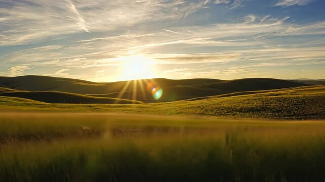 Rolling green hills meet a dynamic blue sky illuminated by golden sunlight and wispy clouds, creating a serene and peaceful countryside vista.