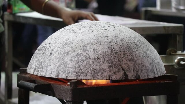 Cast iron pan used to make rotis being heated upside down by the flames