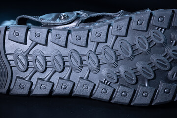 A detailed macro view of a textured rubber shoe sole showing oval tread patterns and screw-like...