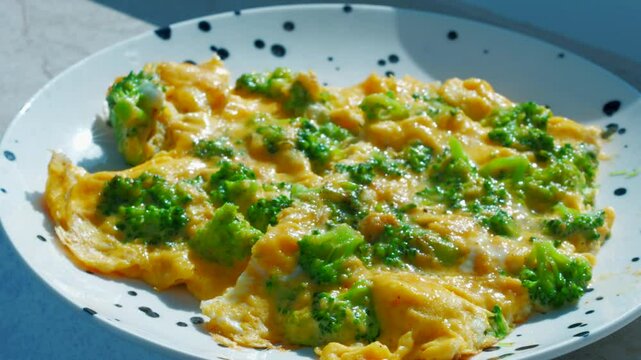 Yellow omelette in a frying pan with vegetables and cheese.
Scrambled eggs with cheese in a hot frying pan close-up.
A person stirs an omelette with a spatula.
Fresh raw eggs