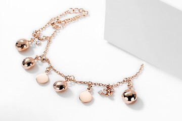 A chic rose gold anklet with dainty charms photographed on a white background
