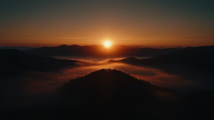 Dramatic sunset illuminates a mountainous landscape with a misty valley