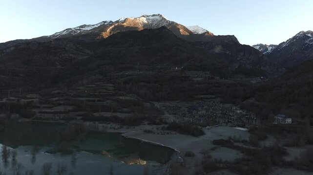 Aerial shot - Sunlight slowly illuminates the peak of Pena Telera reflected in the Ibon de los Banos lake in the Tena Valley, Spanish Pyrenees, Huesca, Aragon, Spain