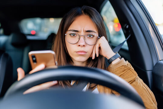 Fototapeta Stressed and worried woman sitting in car holding phone and waiting, received bad news, planning route, traffic jam, thinking about family problems or relationship issues, feeling sad and anxious
