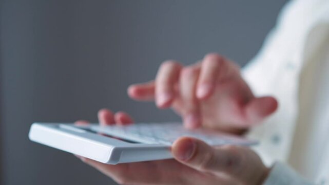 A man counts on a calculator while standing in a bright office.
Counting money on a calculator.
An accountant uses a calculator.
Income and expenses.
Banker, money, count, accountant