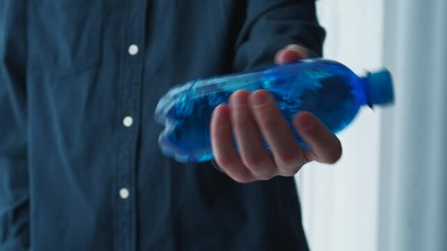 Blue plastic bottle close-up in hands.
Cool drink in a bottle.
Ungassed water in a bottle.
Half-liter bottle with water.
Container with water