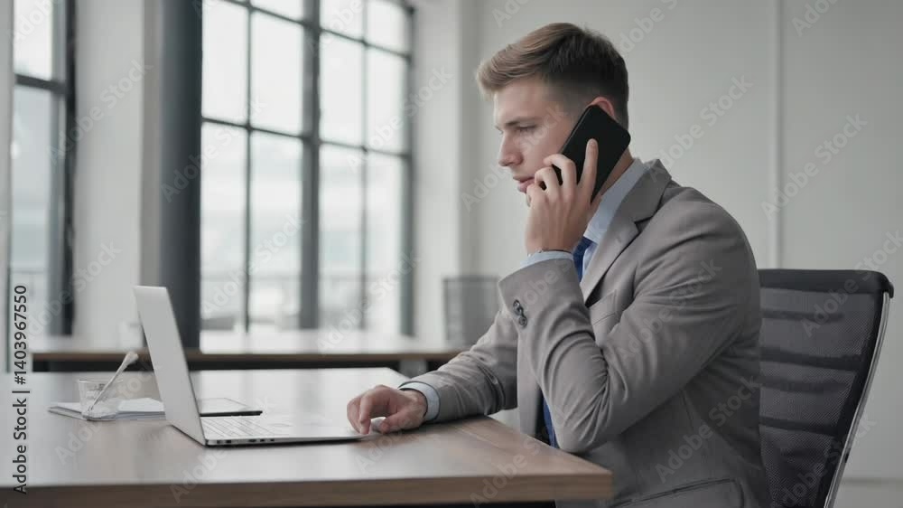 Poster a person sitting at a desk using a cell phone, possibly discussing work or personal matters.