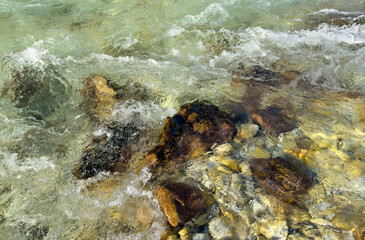fast-flowing clear water over smooth river stones, with visible textures and light reflections. natural balance of motion, river power