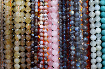 Strands of colorful natural agate and rose quartz beads, labradorite beads on the gemstone market.