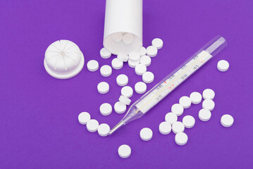 Glass thermometer between red pills and purple capsules