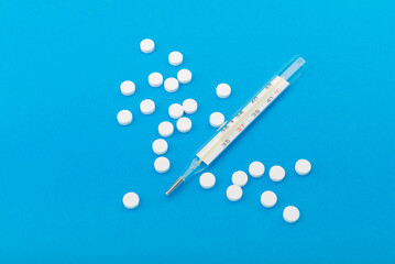 Glass thermometer between red pills and blue capsules