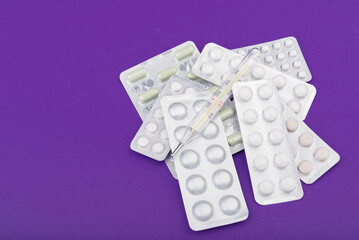 Glass thermometer between red pills and purple capsules