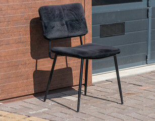 black office chair with fabric upholstery stands outside on the street in front of a building