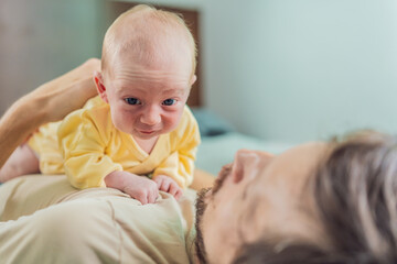 A newborn baby rests peacefully on the father's chest, feeling the warmth and heartbeat of his...