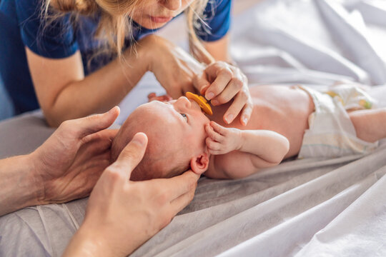 A newborn baby receives gentle osteopathic care, lying calmly while the specialist carefully examines and adjusts the infant. A moment of professional pediatric care, early development, and holistic