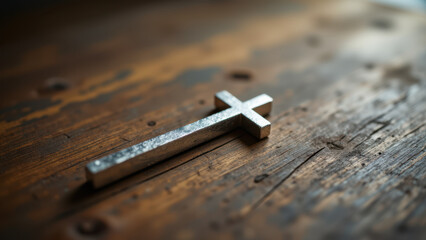 The silver cross atop a weathered wooden surface symbolizes faith and spirituality within Christian traditions.