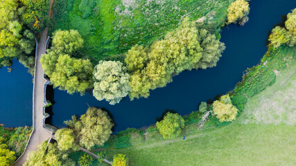 Aerial View of Winding River and Footbridge Surrounded by Trees and Grassland – Scenic Countryside Landscape in Summer