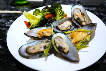 Delicious plate of cooked mussels with fresh herbs. Perfectly presented, vibrant colors, and appetizing texture. Ideal for food, gourmet, and culinary themes.

