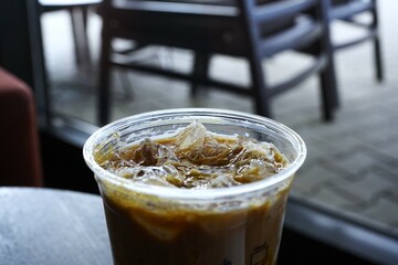 Iced coffee served in a transparent glass with visible ice cubes, creating a refreshing and energizing look. Perfect for themes of summer drinks, caffeine boost, or café lifestyle.