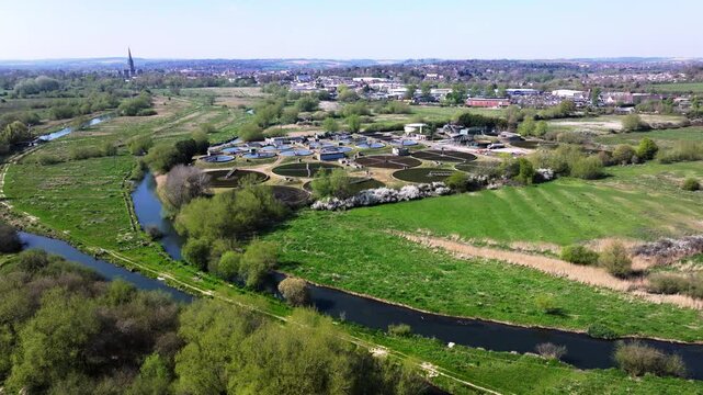 Aerial tracking shot of Sewerage farm on the River Avon with Salisbury in the distance. Wiltshire UK