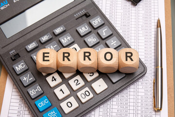Wooden cubes with ERROR text on calculator with spreadsheets and financial data