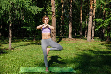 Beautiful girl practices yoga in the park.