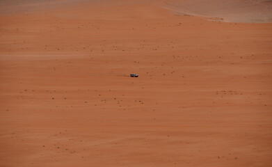 A Car Drives Through the Striking Red Sands of Wadi Rum Desert in Jordan, a Breathtaking UNESCO...