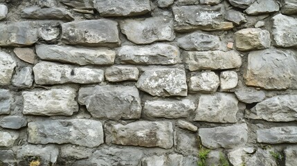 Fototapeta premium A gray stone wall made of rough uneven rocks stacked together.