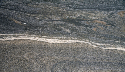Granite texture with horizontal white vein and gray layered rough surface, close-up
