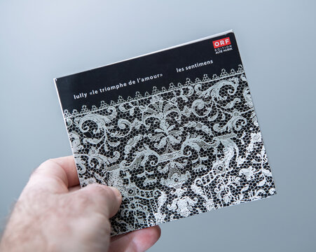 Paris, France - Feb 7, 2025: A hand holds a classical music CD titled Le Triomphe de l' Amour by Lully featuring ornate lace artwork on the cover and branding from ORF Edition Alte Musik