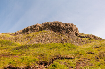 A rocky hillside with a few green patches of grass