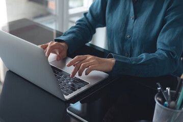 Businesswoman working on laptop computer at modern office. Asian business woman surfing the internet, searching the information on laptop. Young female manager using portable computer