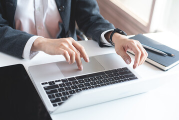 Closeup, Business woman working on laptop computer with digital tablet on office table. Woman hands typing on laptop computer keyboard, searching data, surfing the internet at office