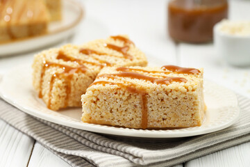 Delicious caramel puffed rice bars on white wooden table, closeup