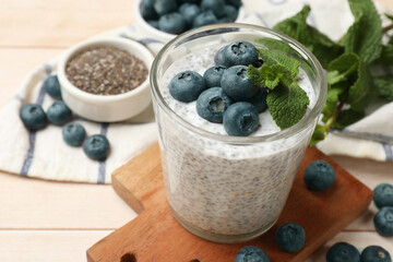 Delicious chia pudding with blueberries and mint in glass on wooden table, closeup