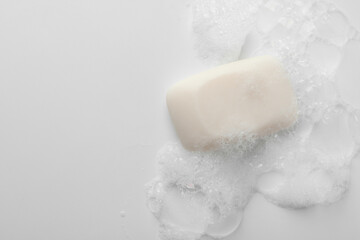 Soap bar with foam on white background, top view. Space for text