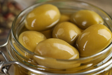 Pickled green olives in glass jar, closeup