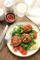 Delicious patties with greens, tomatoes, ketchup and drink on wooden table, flat lay
