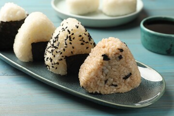 Rice balls (onigiri) on light blue wooden table, closeup. Traditional Japanese dish